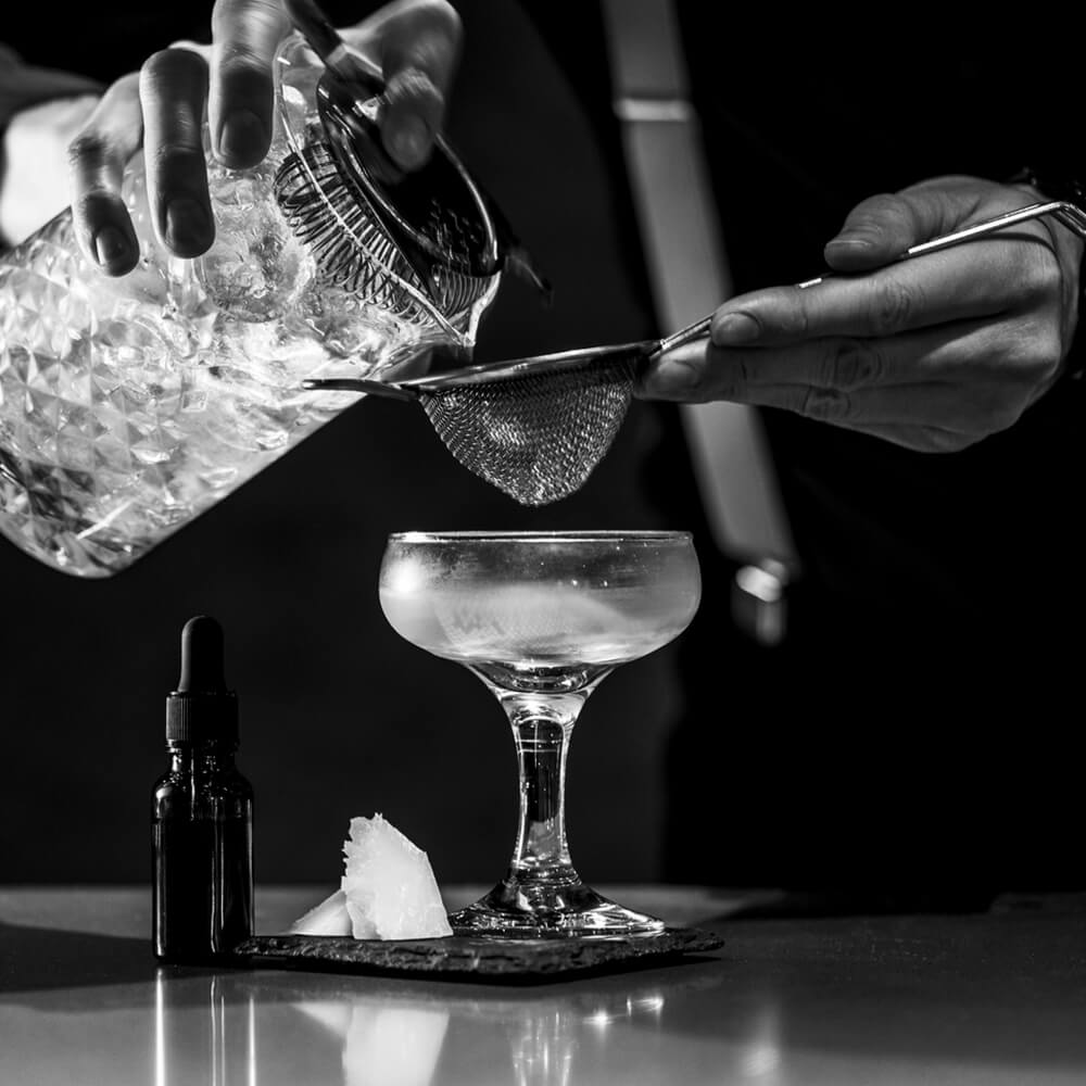 A bartender straining a cocktail into a chilled coupe at The Tollhouse