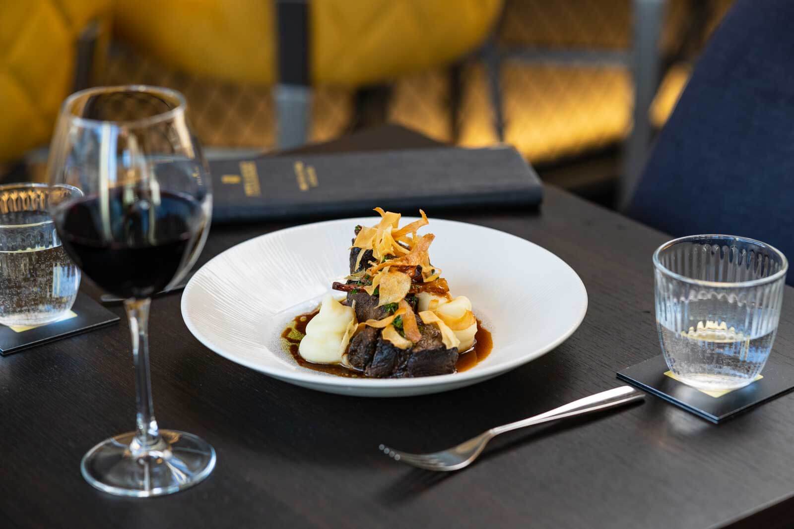 Braised beef with buttered mash, crisp parsnip and a red-wine jus, with a glass of red at the table