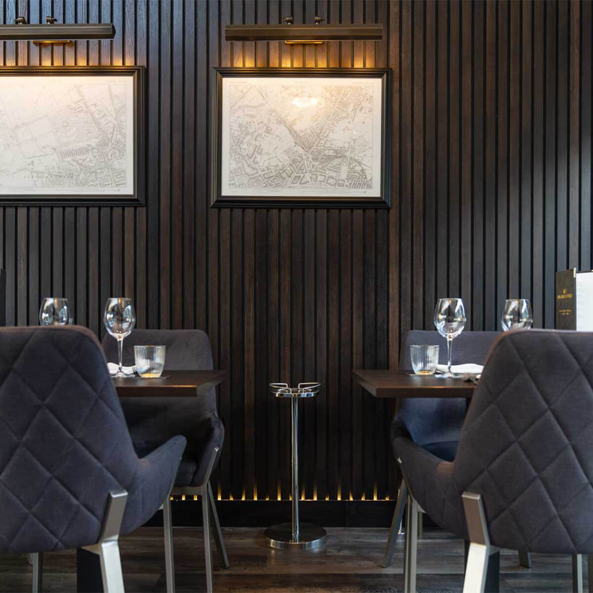 Smoked-oak panelling hung with antique maps of Edinburgh, above navy velvet chairs at set tables